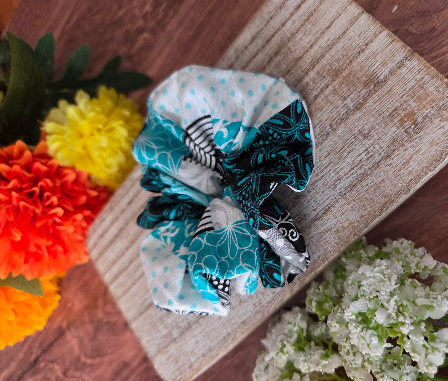 Set of colorful scrunchies on a wooden surface with flowers in the background