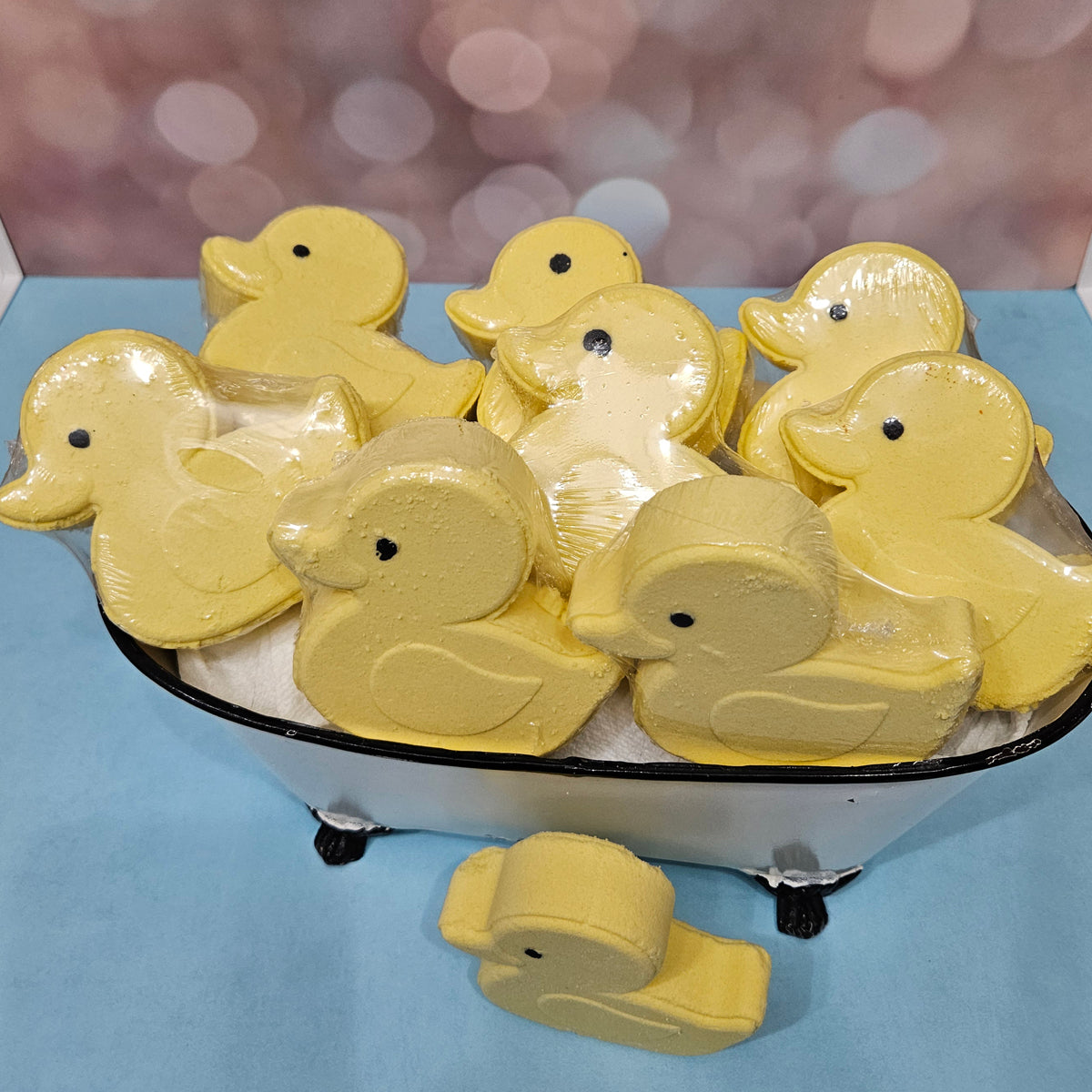 Yellow duck bath bombs in a miniature bathtub.