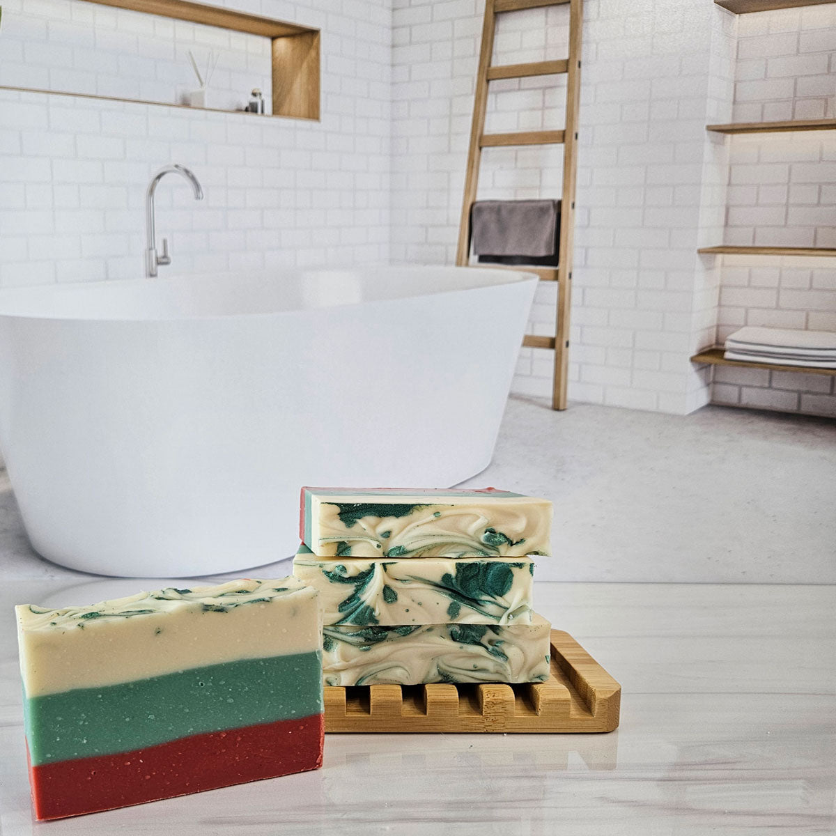 Handmade soap bars on a bamboo dish. One bar is layered red, green, and cream; others are swirled green and cream.