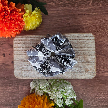 Black and white patterned scrunchie on a wooden board with flowers around