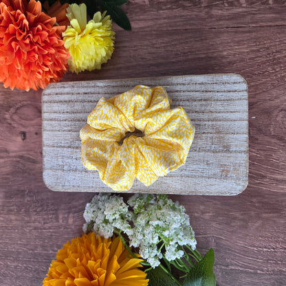 Yellow scrunchie on a wooden board with flowers around