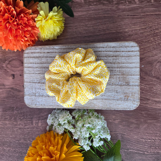 Yellow scrunchie on a wooden board with flowers around