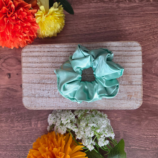 Green scrunchie on a wooden board with flowers around