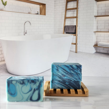 Blue agave soap bars stacked on a wooden rack in a bathroom setting.