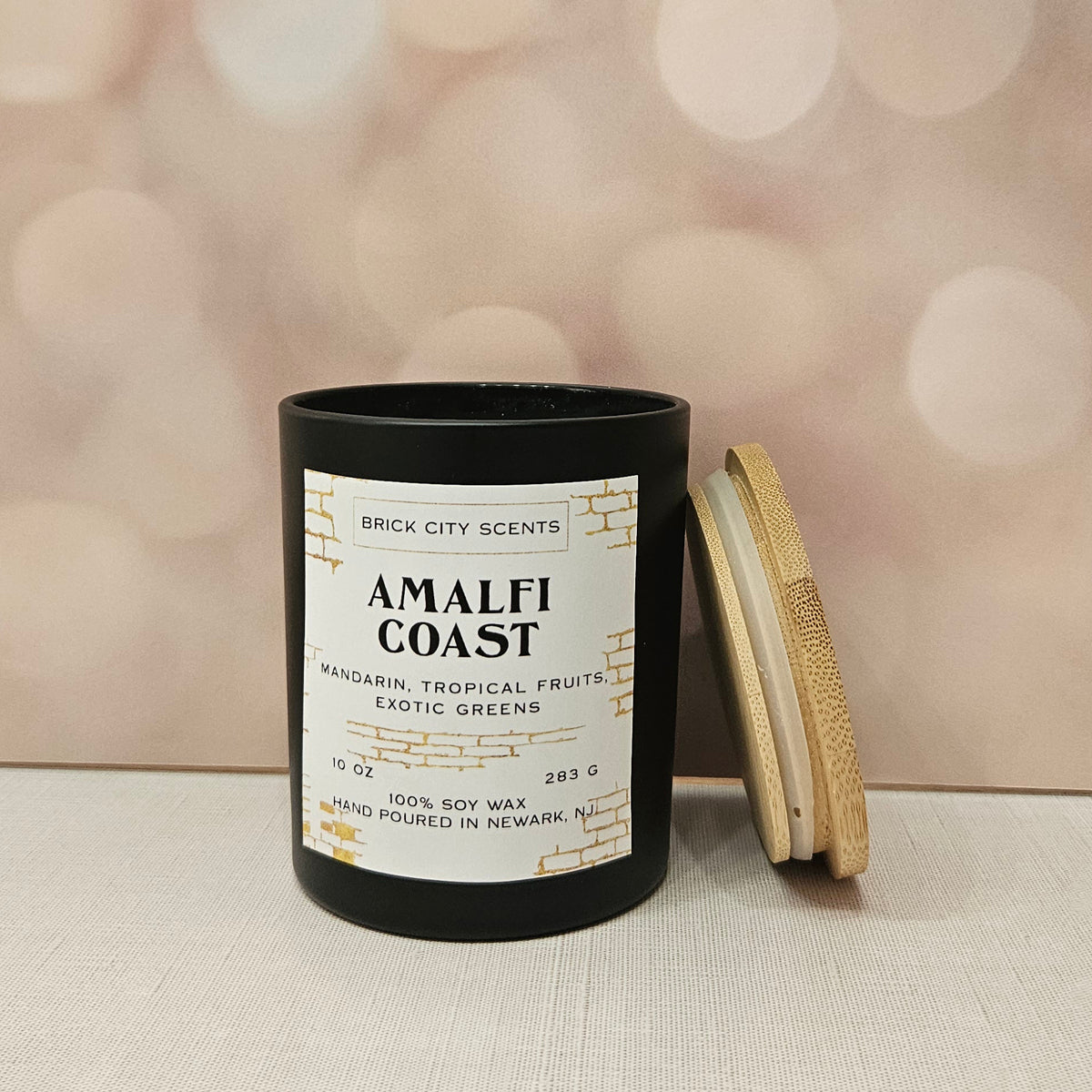 Brick City Scents Amalfi Coast candle in a black jar with a wooden lid. Scent of mandarin, tropical fruits, and exotic greens.