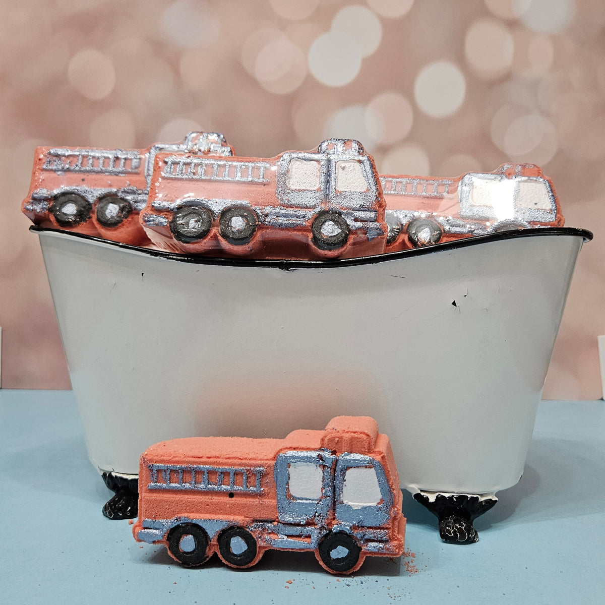 Fire truck bath bombs in a miniature tub, orange with silver accents.