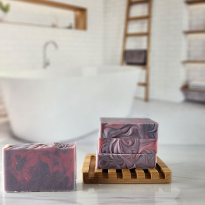 Handmade lavender chamomile soap bars on a bamboo soap dish. Swirled purple and red design.