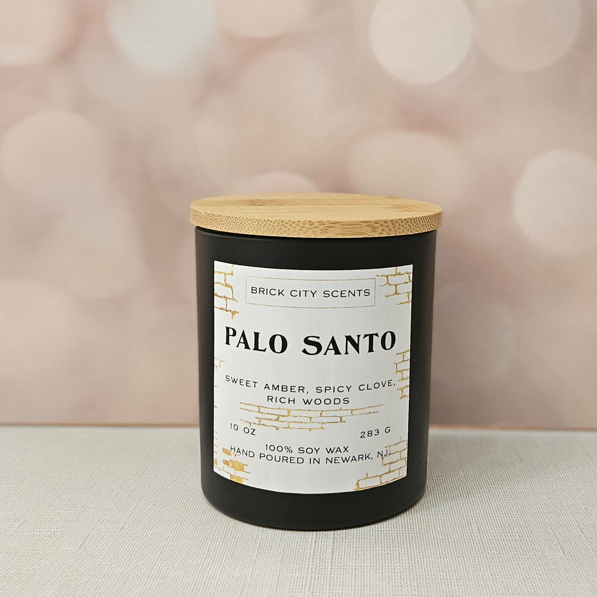 Brick City Scents Palo Santo candle in black jar with wood lid. Sweet amber, spicy clove, rich woods scent. 10 oz, 100% soy wax.