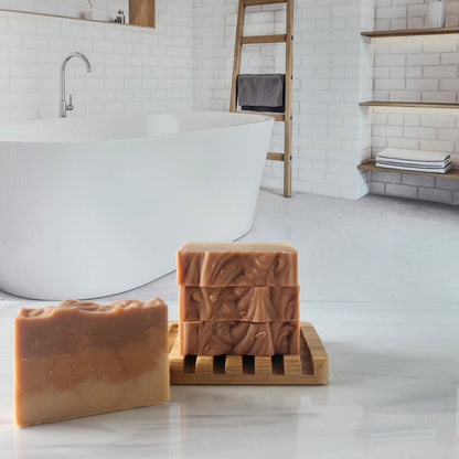 Handmade patchouli sandalwood soap bars on a wooden holder in a bathroom setting.