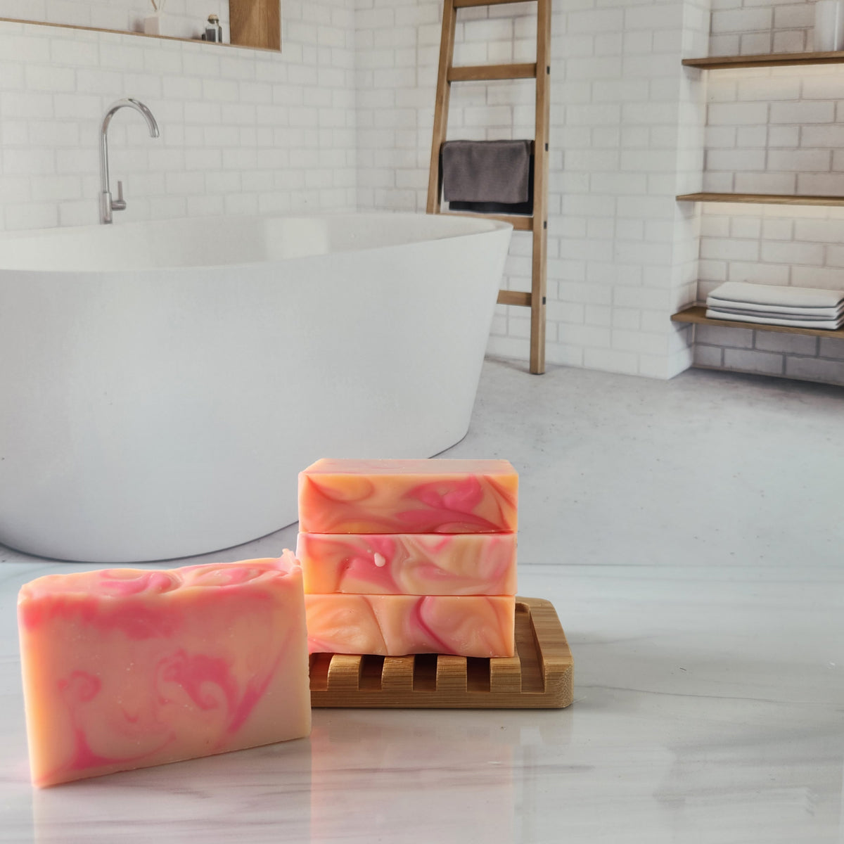 Handmade peony swirl soap bars stacked on a bamboo dish in a bathroom setting.