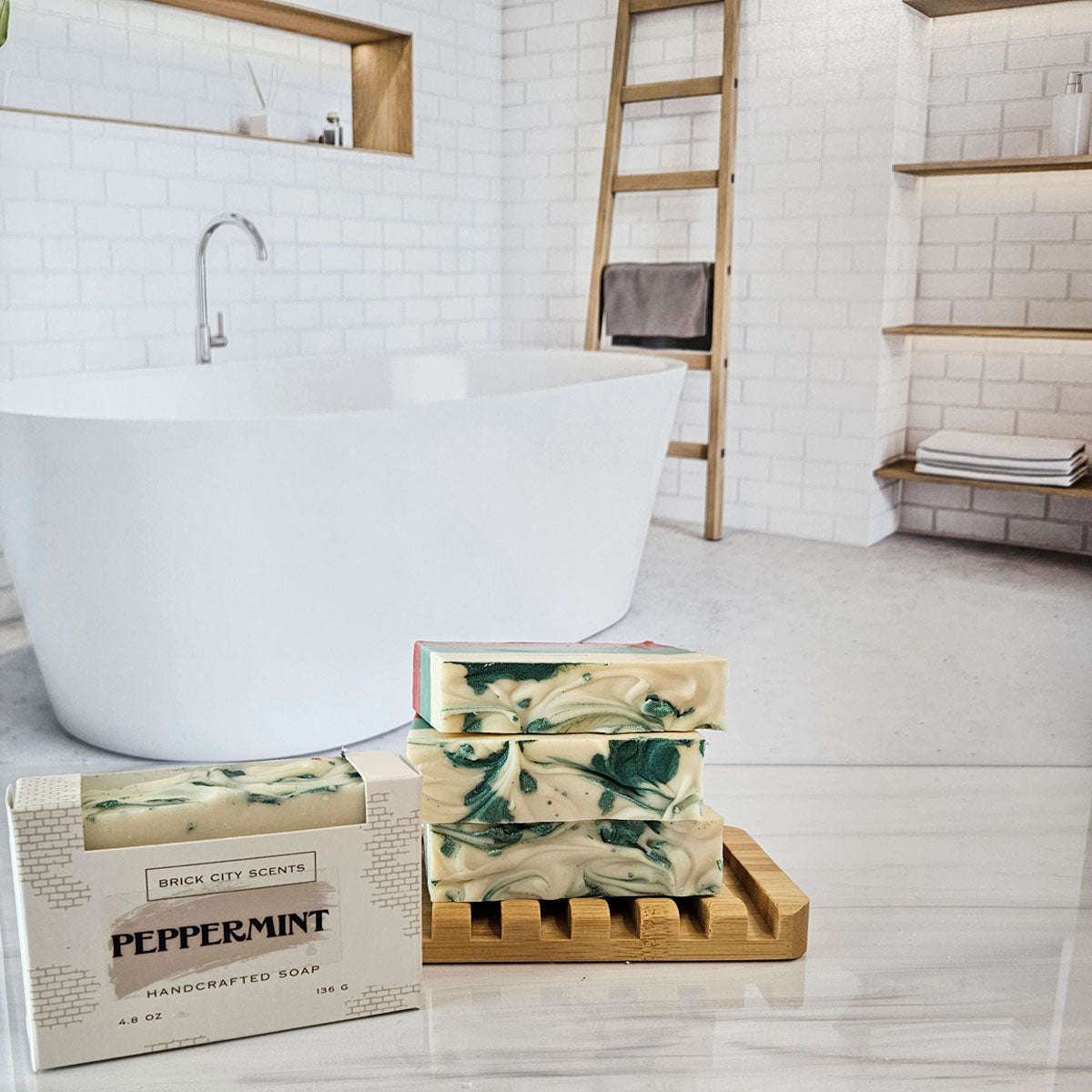 Brick City Scents Peppermint Handcrafted Soap bars and packaged bar on a bamboo soap dish in a white bath setting.