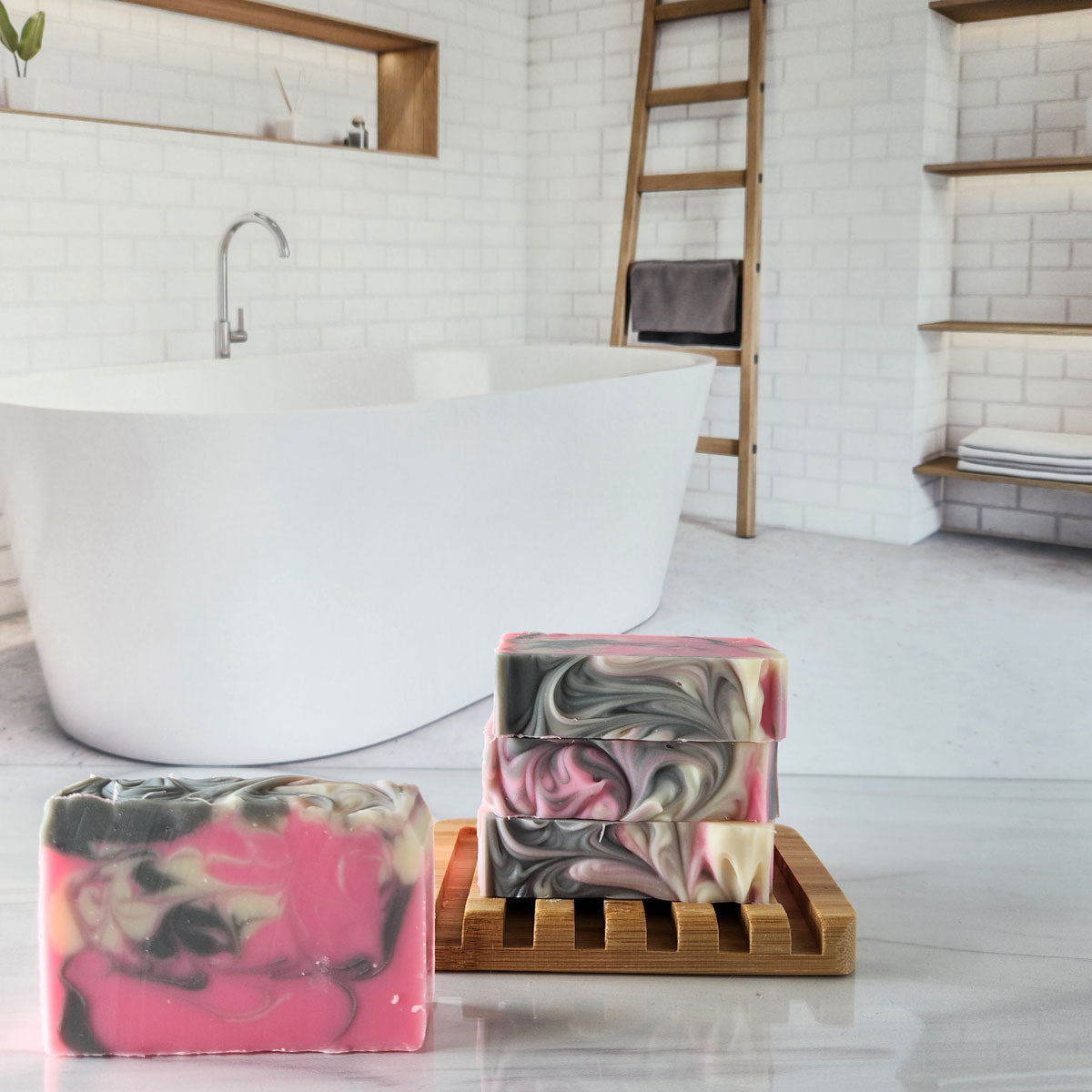 Handmade rose quartz soap bars with pink and grey swirls, stacked on a wooden soap dish.