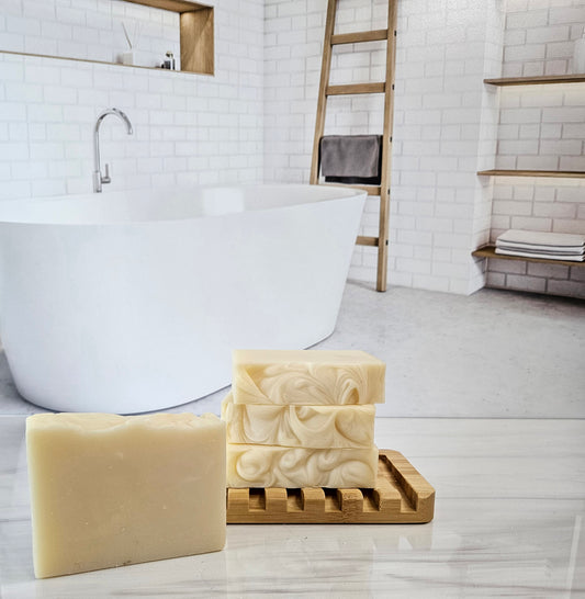 Unscented triple butter soap bars made with shea, cocoa, and mango butter on a wooden soap dish.